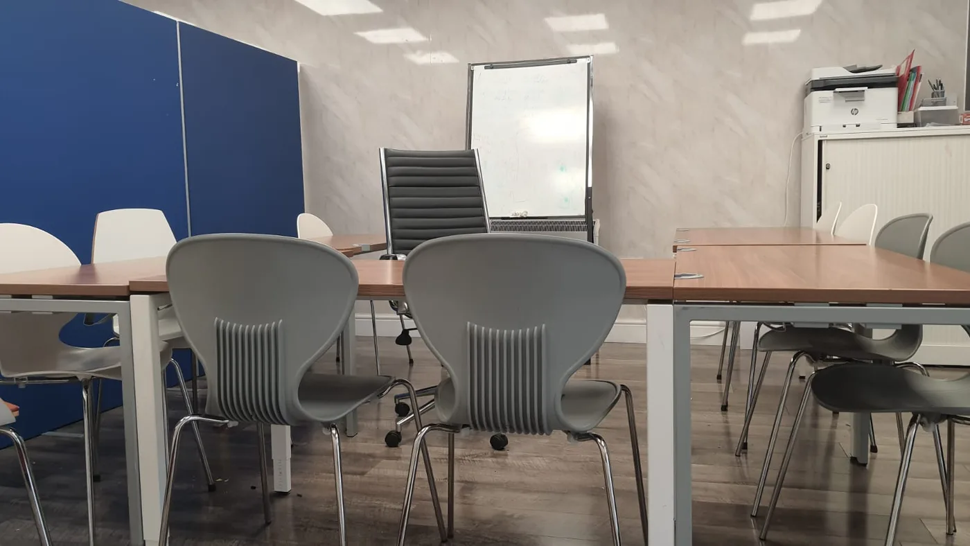 A Peace Home classroom arranged with tables, chairs and a whiteboard.